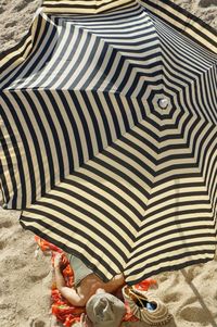 High angle view of person relaxing under sunshade on beach