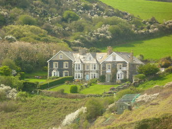 House on field by trees and houses on hill