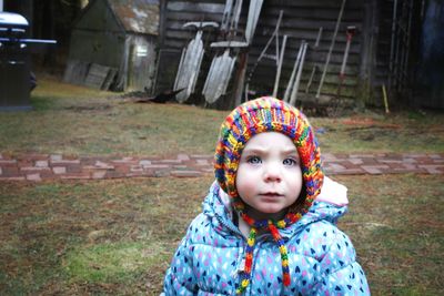 Portrait of baby girl in warm clothes standing outdoors