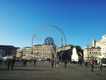 People in amusement park against blue sky