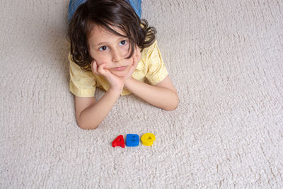 Portrait of cute girl lying down on floor at home