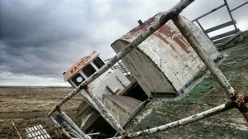 Low angle view of abandoned building against cloudy sky