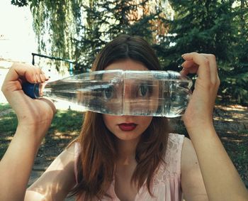 Portrait of woman looking through water bottle