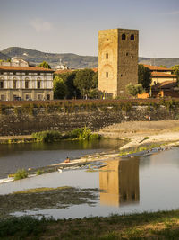 Old building by river against sky