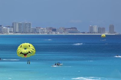 Smiley face parachutes over sea against clear sky
