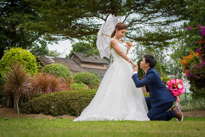 Side view of smiling young bride with groom romancing in park