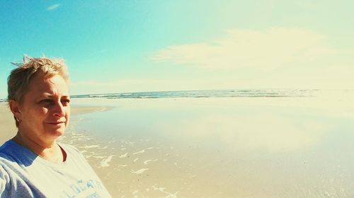 Young man at beach against sky