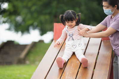 Portrait of smiling young woman sitting on wooden wall