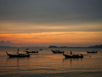 Silhouette boats in sea against sky during sunset
