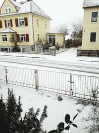 Snow covered houses by building during winter