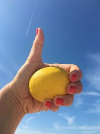 Midsection of person holding ice cream against blue sky