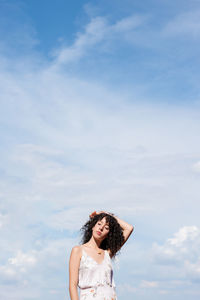 Portrait of young woman standing against sky