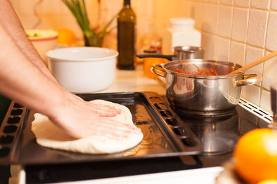 Cropped hands kneading dough in tray