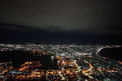 High angle view of illuminated city against sky at night