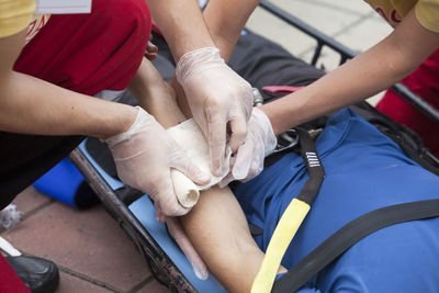 Midsection of healthcare workers bandaging patient on stretcher