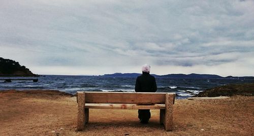 Rear view of man standing by sea against sky