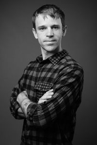 Portrait of young man standing against gray background