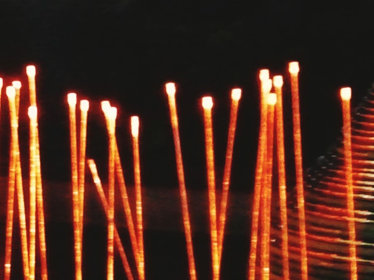 CLOSE-UP OF ILLUMINATED BURNING CANDLES AT NIGHT