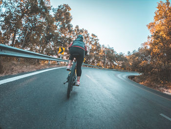 Rear view of man riding motorcycle on road