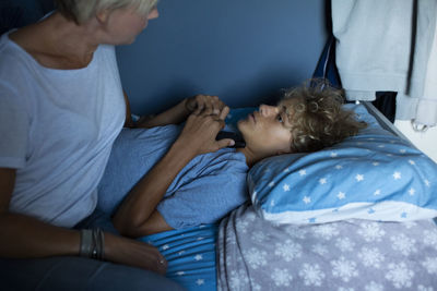 Boy talking with mother while lying on bed at home
