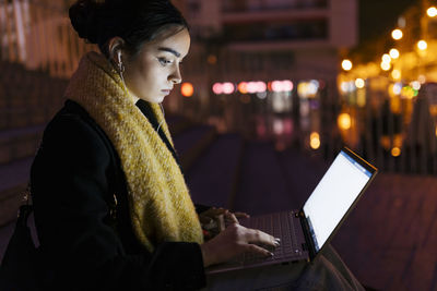 Teenage girl using laptop in city