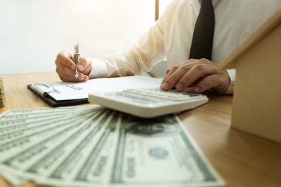 Midsection of real estate agent using calculator at office