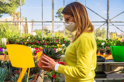 Side view of woman standing against yellow flowering plants