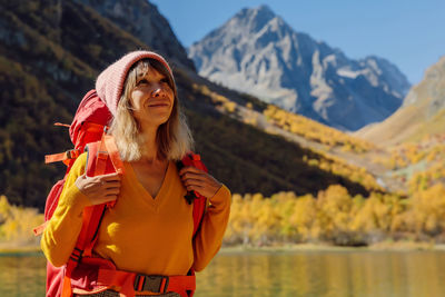 Young woman standing against snowcapped mountain