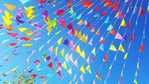 Low angle view of colorful bunting flags against clear blue sky