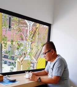 Side view of young man using mobile phone on table