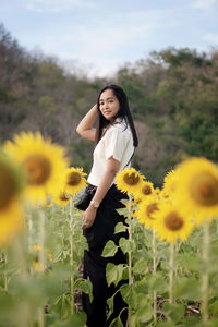 Portrait of young woman standing amidst sunflowers