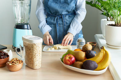 Raw foodism,woman cutting banana for blender, dietary plant based eating for vegan or vegetarian