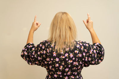 Rear view of woman with arms raised against white background