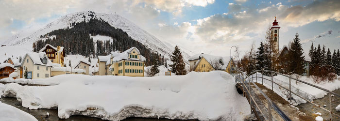 Panoramic view of snow covered trees and buildings against sky