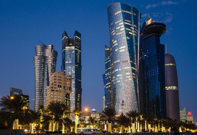 Low angle view of illuminated buildings against blue sky