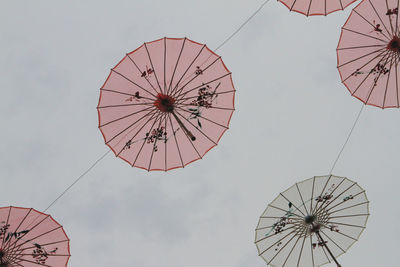 Low angle view of umbrellas hanging against sky