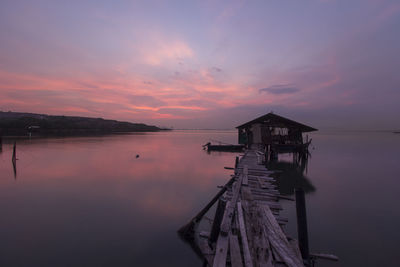 Pier over lake against sky during sunset