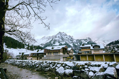 Houses by snow covered mountains against sky