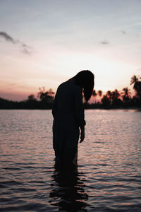 Head down woman standing in silhouette on the beach