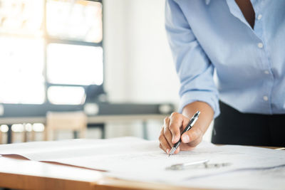 Midsection of man holding paper on table