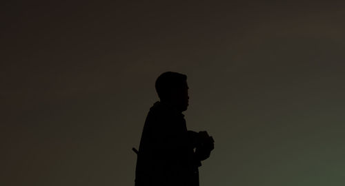 Side view of silhouette man standing against sky