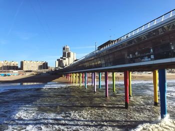 Bridge over river amidst buildings against clear blue sky