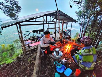 People sitting by bonfire against sky