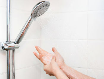 Woman washing hands with soap in shower.