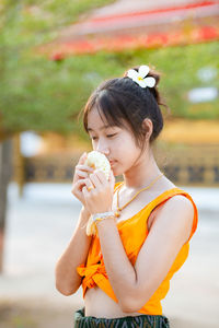 Side view of young woman drinking water at park