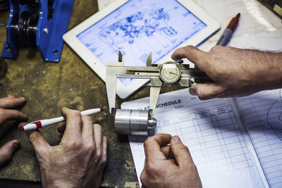 Cropped image of mechanics measuring metal with adjustable caliper at auto repair shop