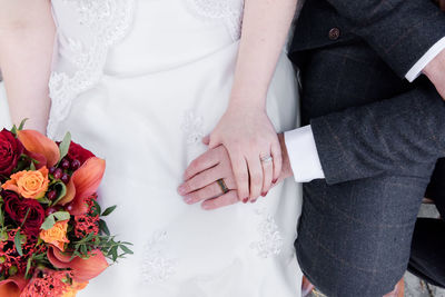 Midsection of couple holding bouquet