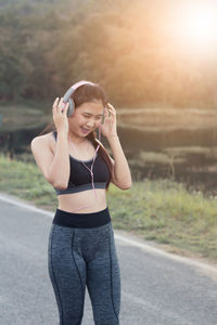 Young woman listening to music while standing on road