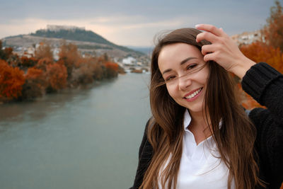 Portrait of young adult caucasian woman against river and castle ruins at background