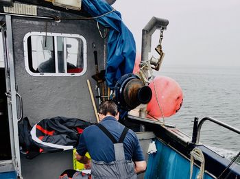 Rear view of man working in sea